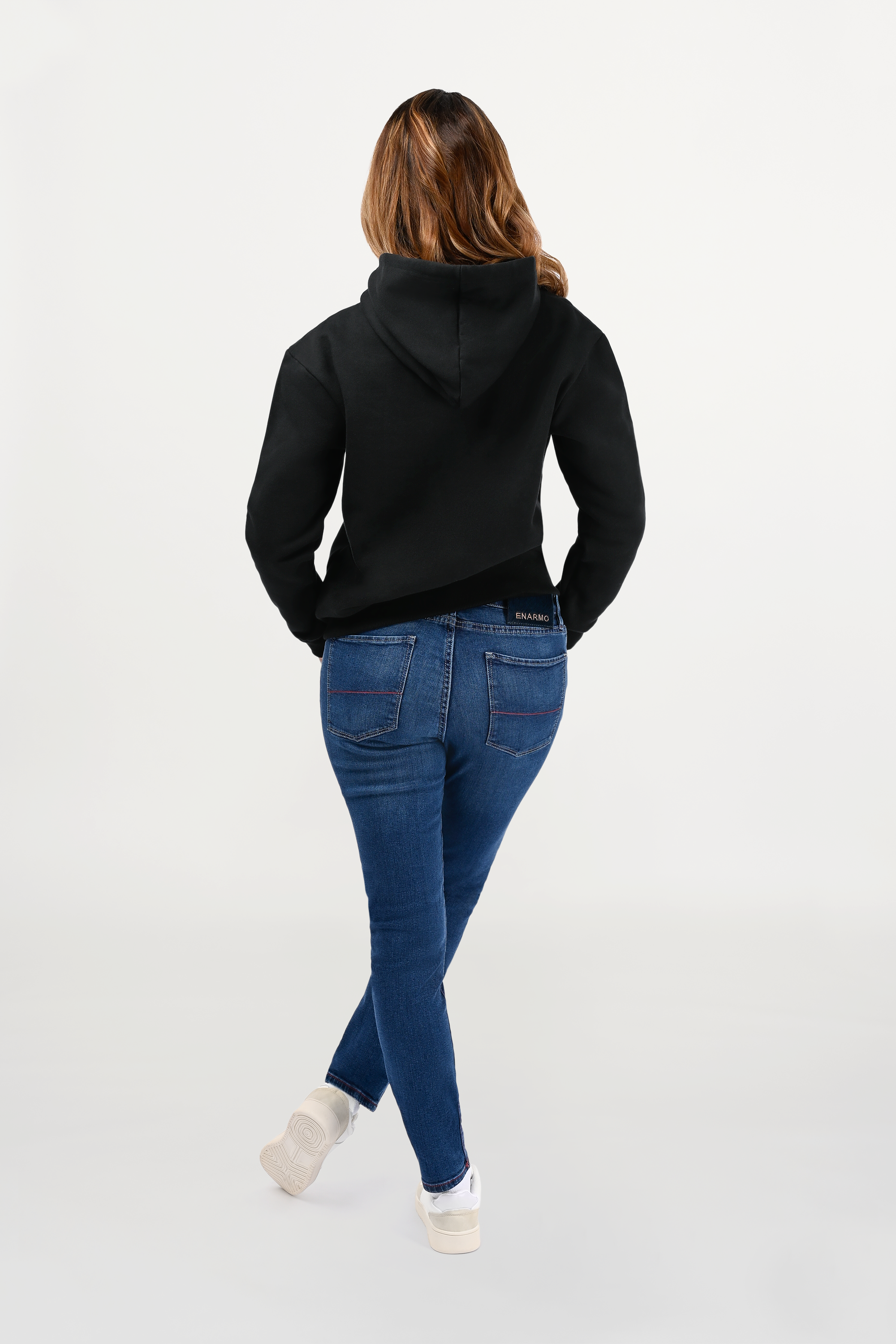 Back view of female model in black designer hoodie, clean rear construction with balanced fit and minimalist luxury appeal.