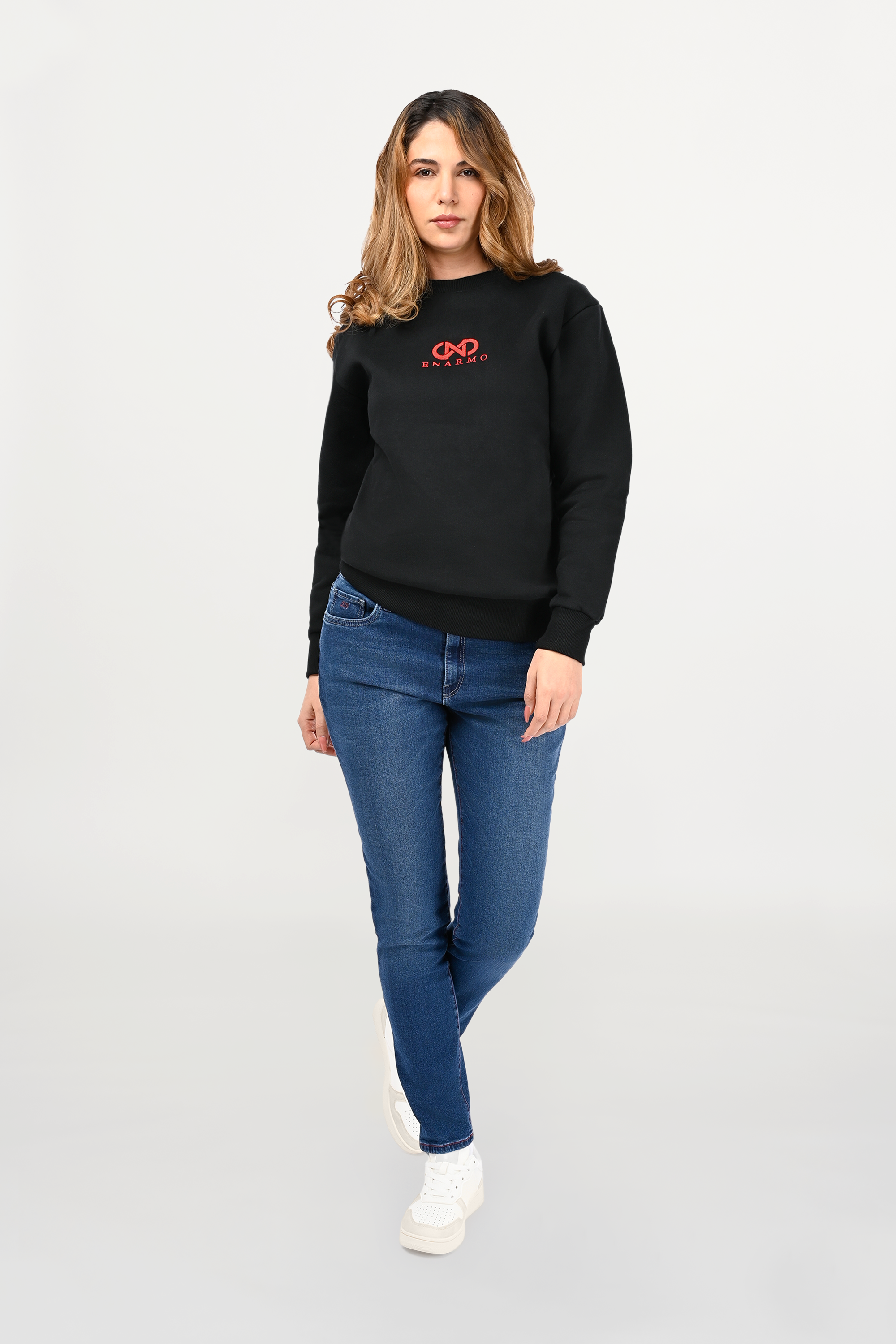 Female model wearing black cotton crewneck with red ENARMO logo embroidery, regular fit silhouette and refined minimalist styling.