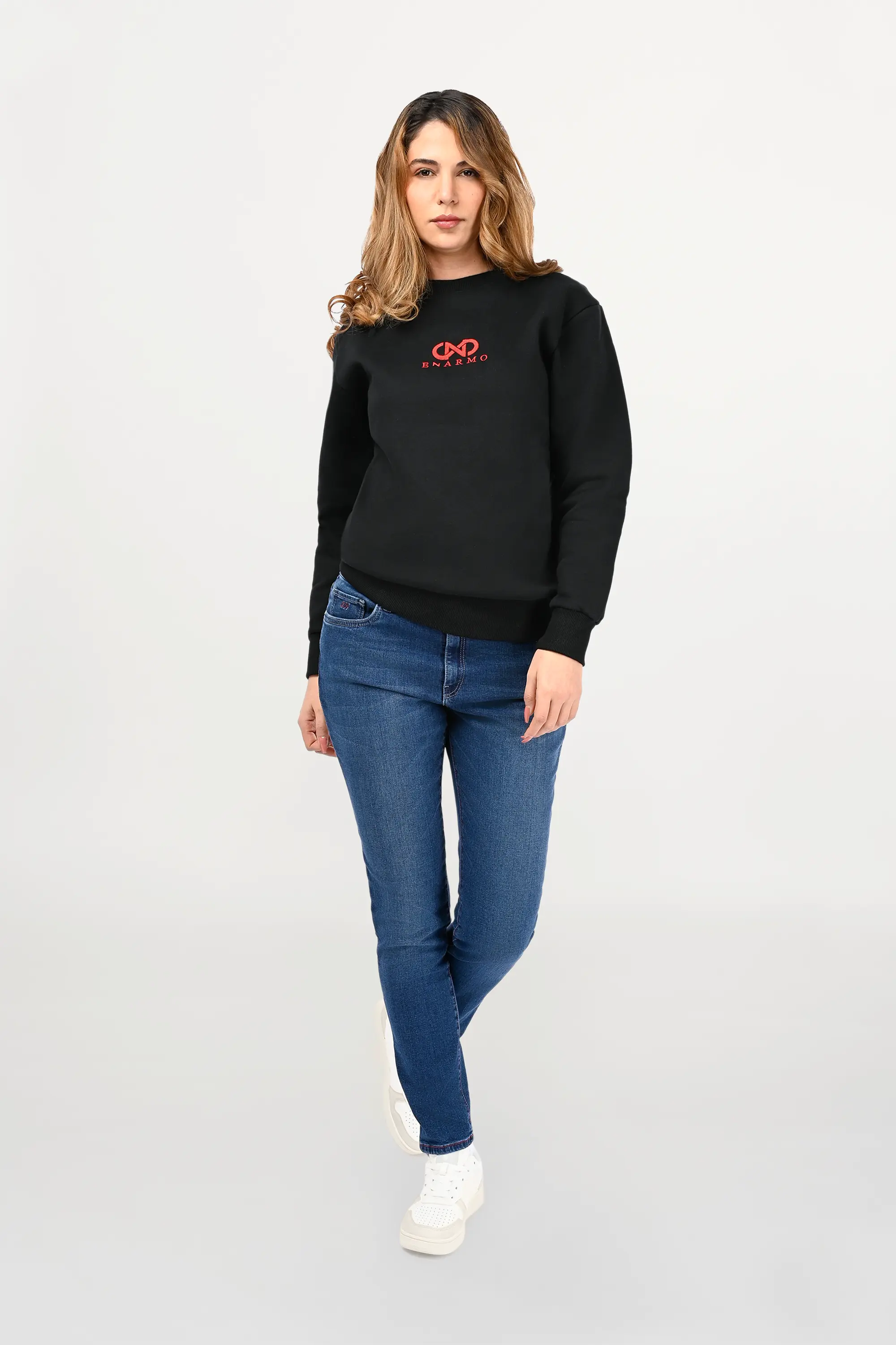 Female model wearing black cotton crewneck with red ENARMO logo embroidery, regular fit silhouette and refined minimalist styling.