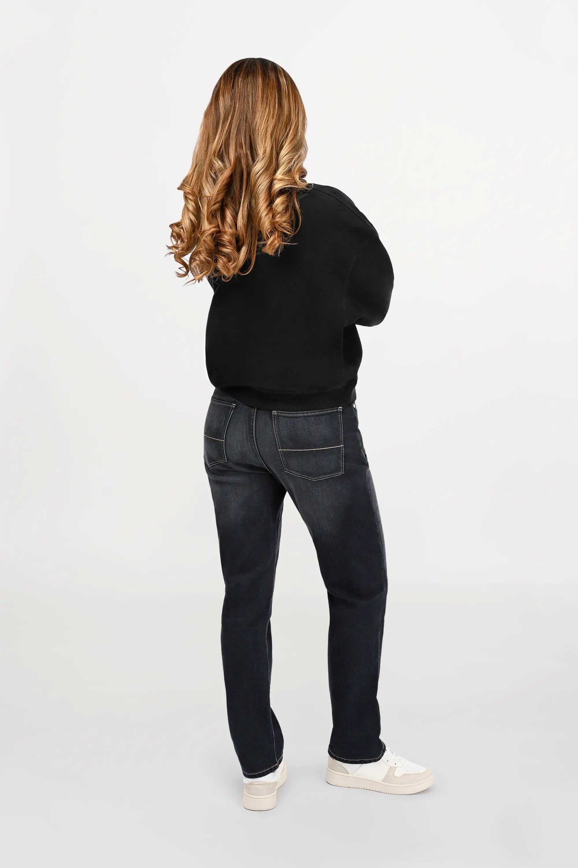 Back view of female model in black oversized ENARMO sweatshirt, clean rear design, loose silhouette and modern luxury aesthetic
