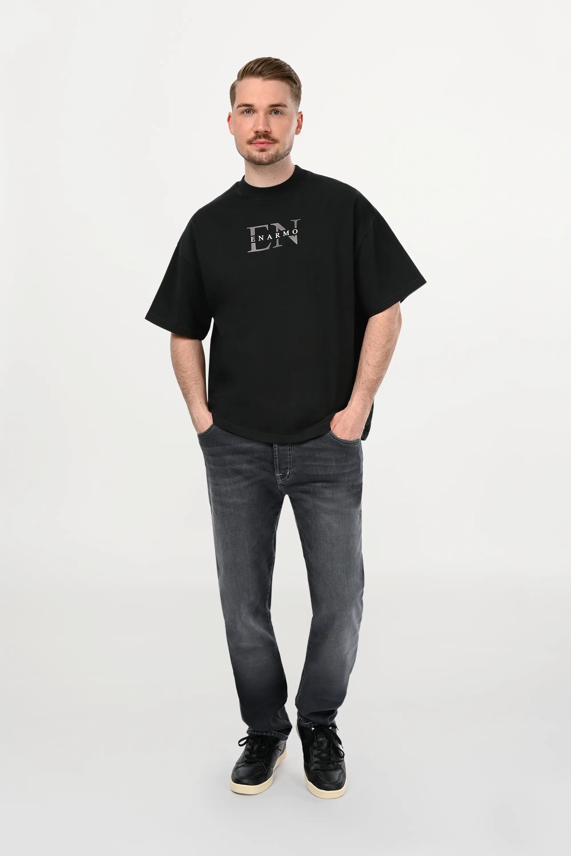 Black oversized cotton T-shirt with anthracite EN monogram worn by male model, front view, modern minimalist luxury streetwear silhouette