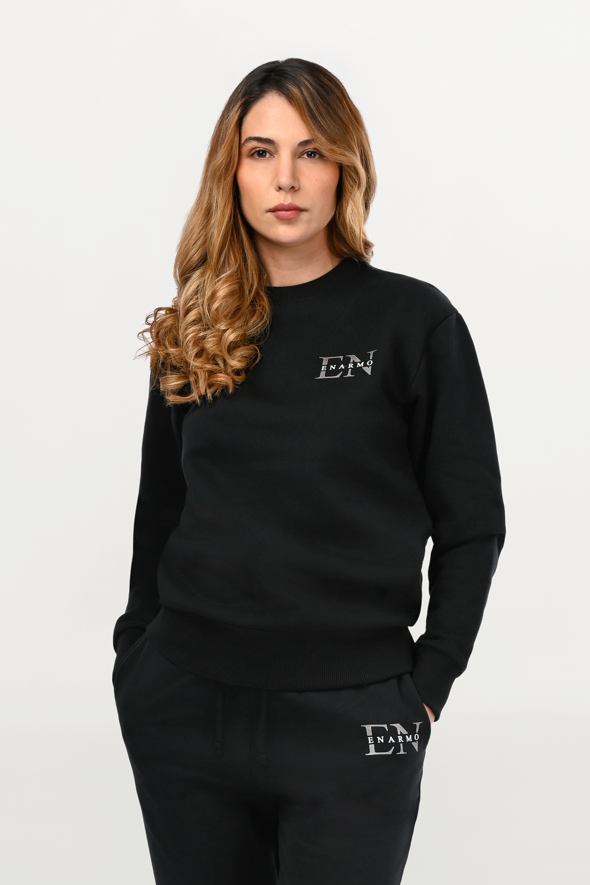 Close-up of EN monogram detail on black cotton sweatshirt, anthracite EN with white ENARMO lettering on structured fabric surface.