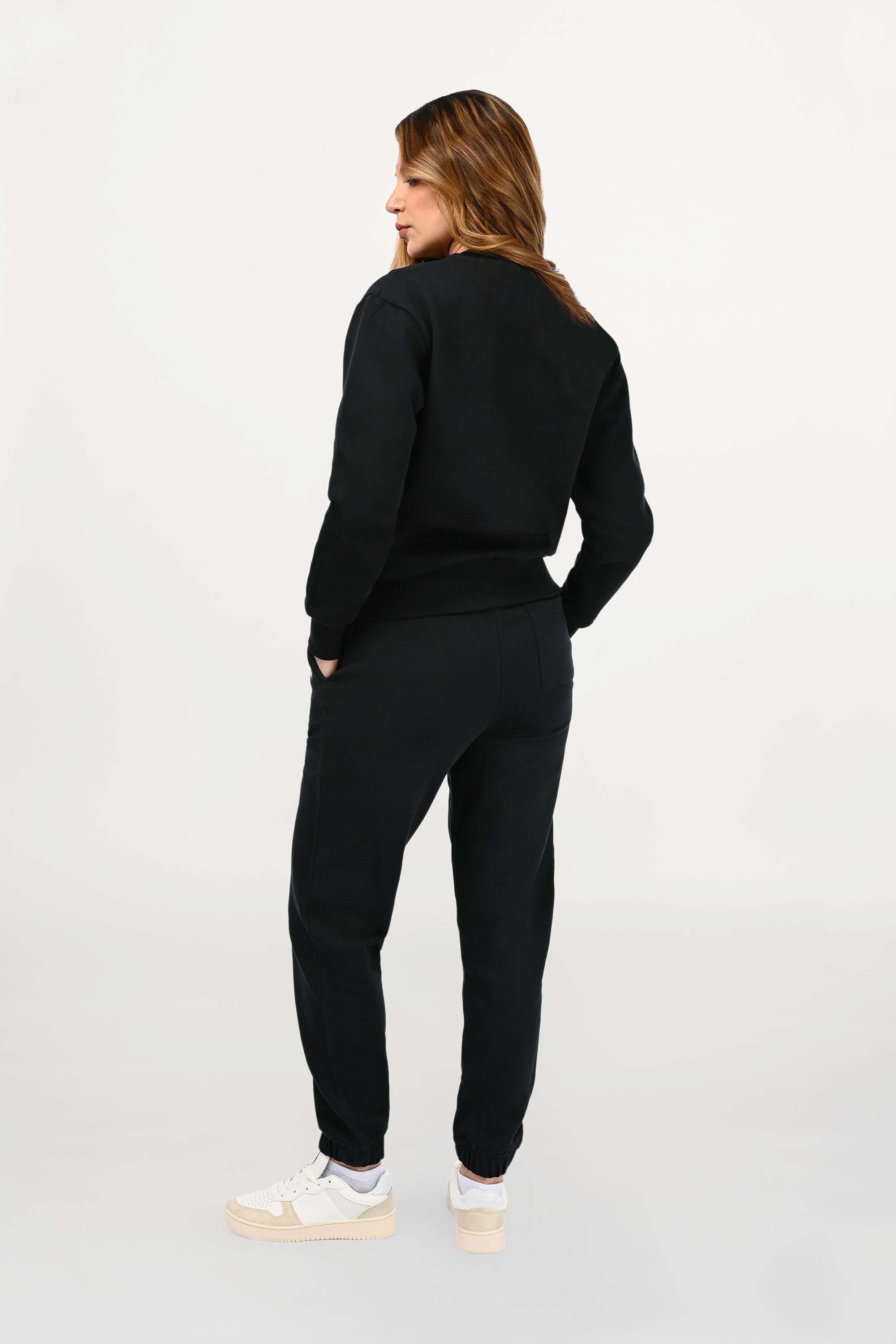 Back view of female model in black ENARMO crewneck, clean rear design, balanced regular cut and minimalist luxury aesthetic.