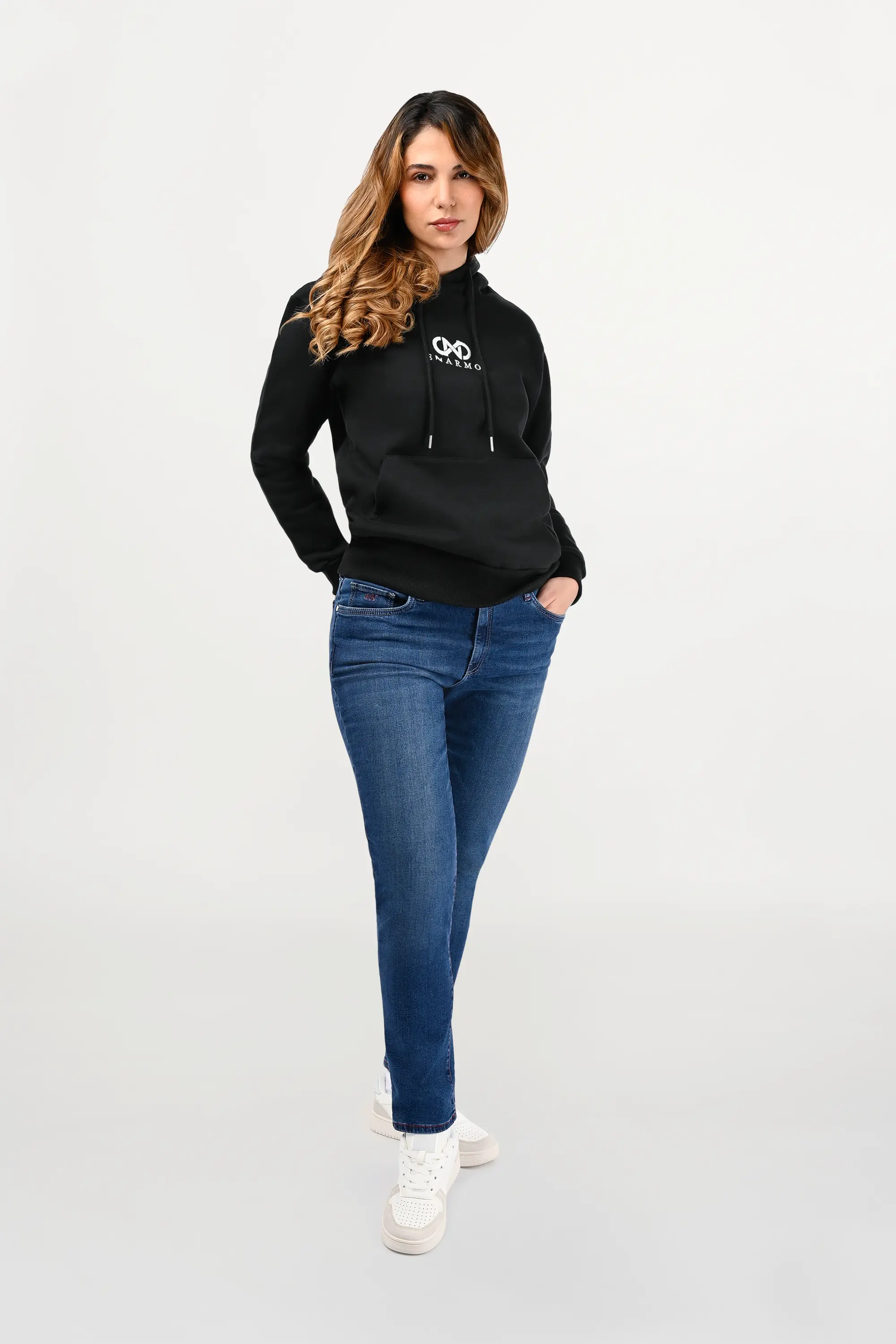 Female model wearing a Sabiha mid blue skinny jeans, sleek silhouette with subtle wash and premium stretch, modern designer denim front view.