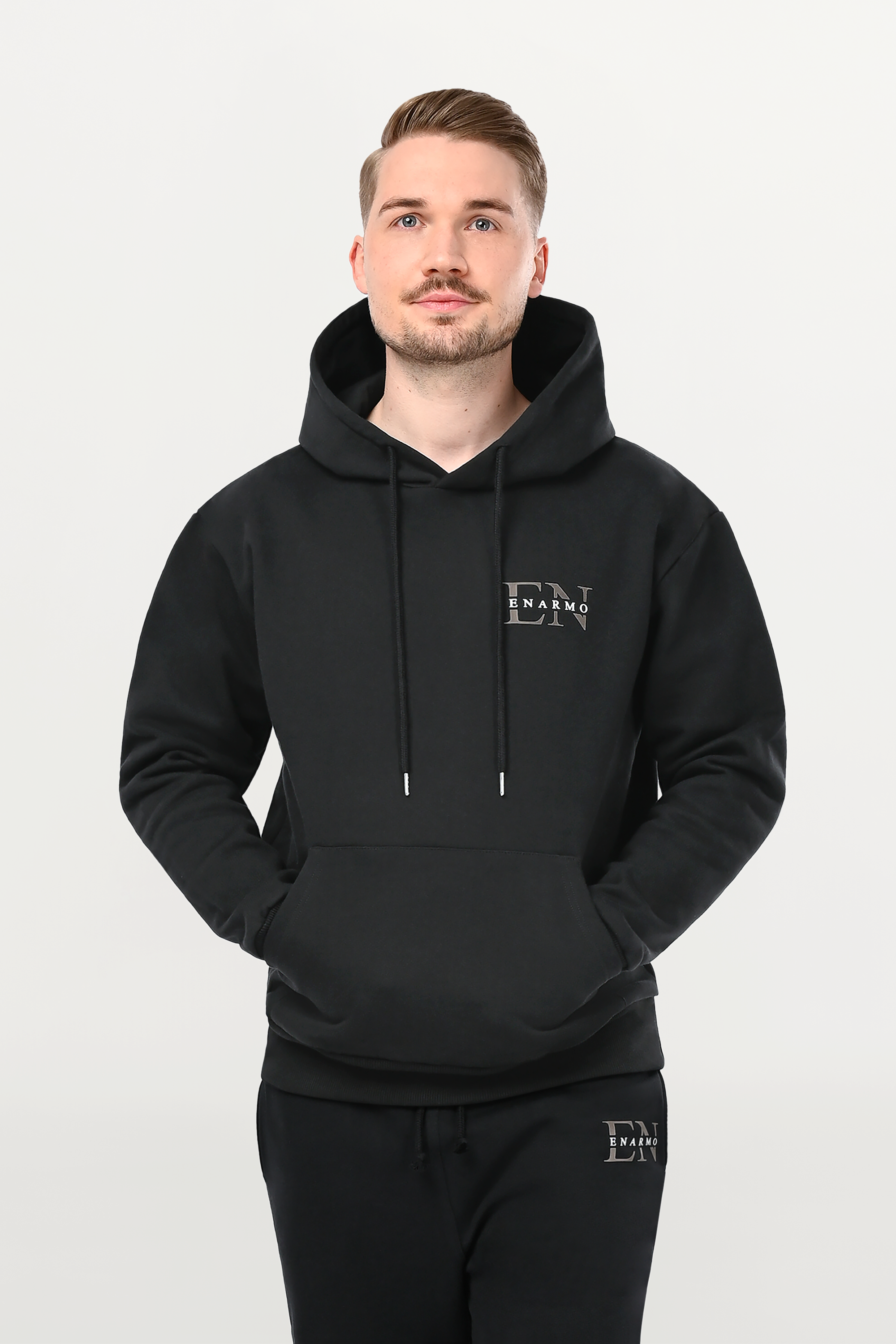 Detailed close-up of anthracite EN Monogram with white ENARMO lettering on black cotton hoodie, precise chest placement and smooth fabric texture.
