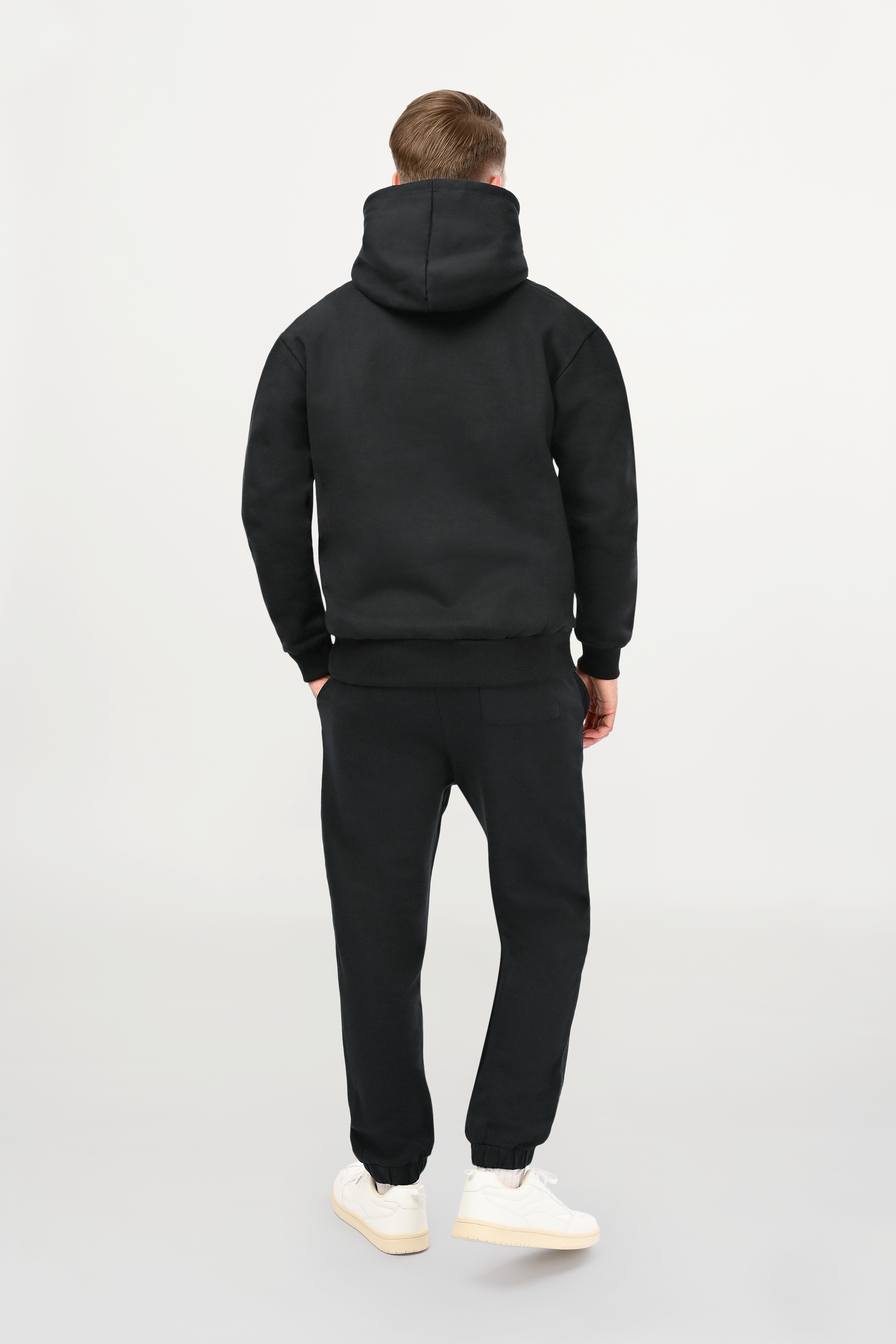 Rear view of male model in black designer hoodie with smooth back panel and structured regular cut.