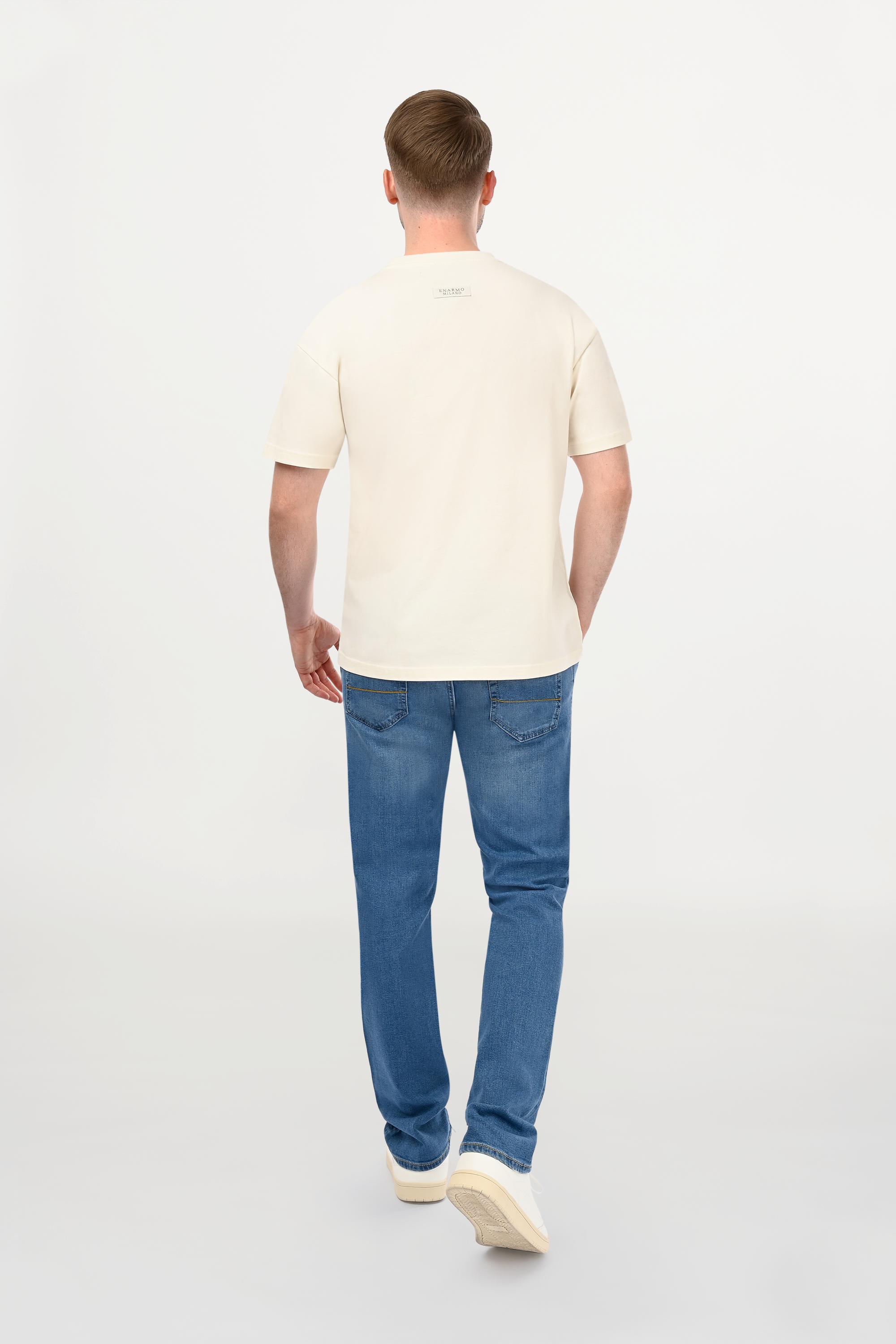 Rear view of male model in light blue slim fit jeans with structured back pockets and clean contemporary denim profile.