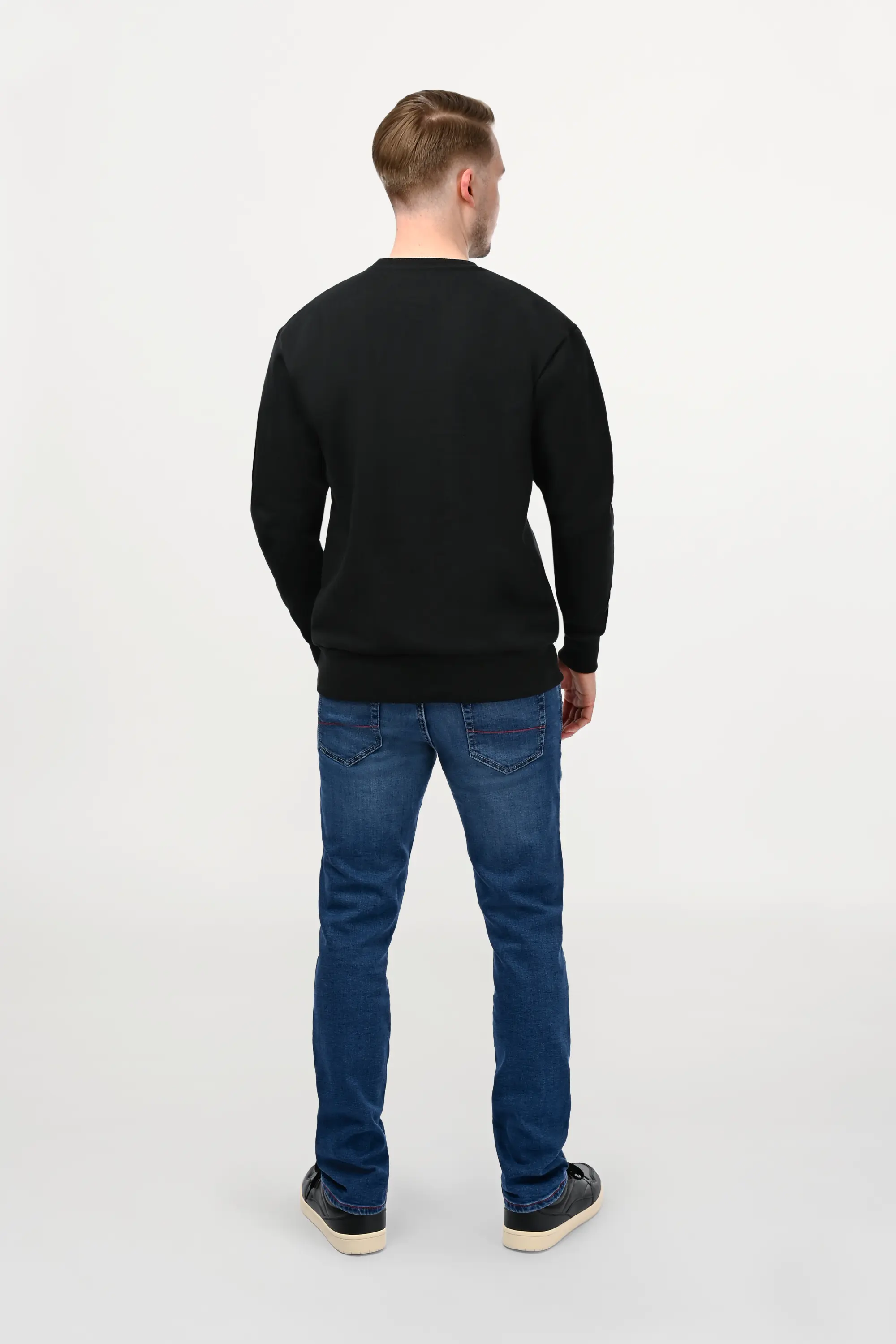 Rear view of male model in a mid blue regular fit jeans with clean back pockets and timeless straight-leg silhouette.