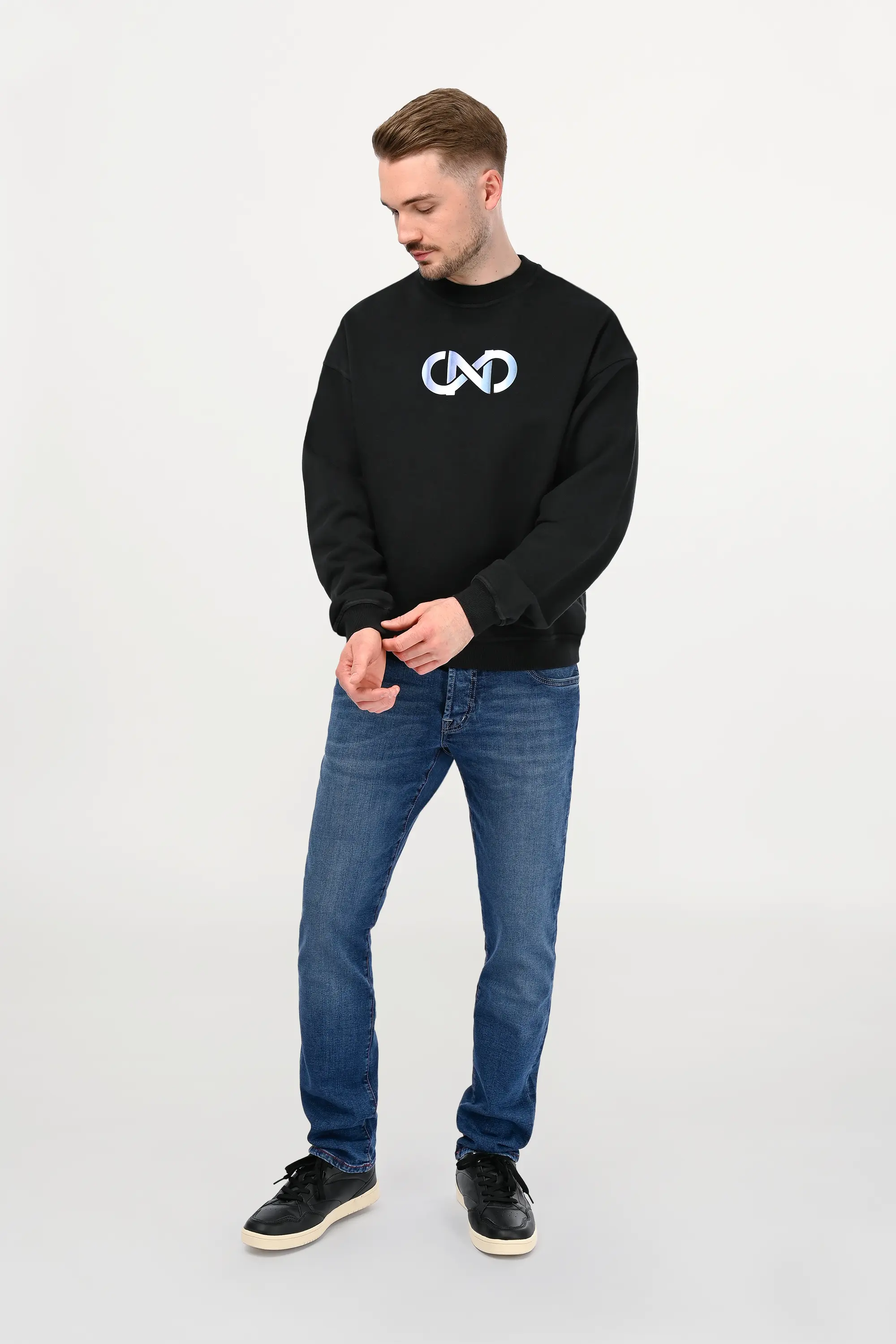 Male model wearing mid blue regular fit denim jeans with subtle wash and classic five-pocket construction, modern designer denim front view.
