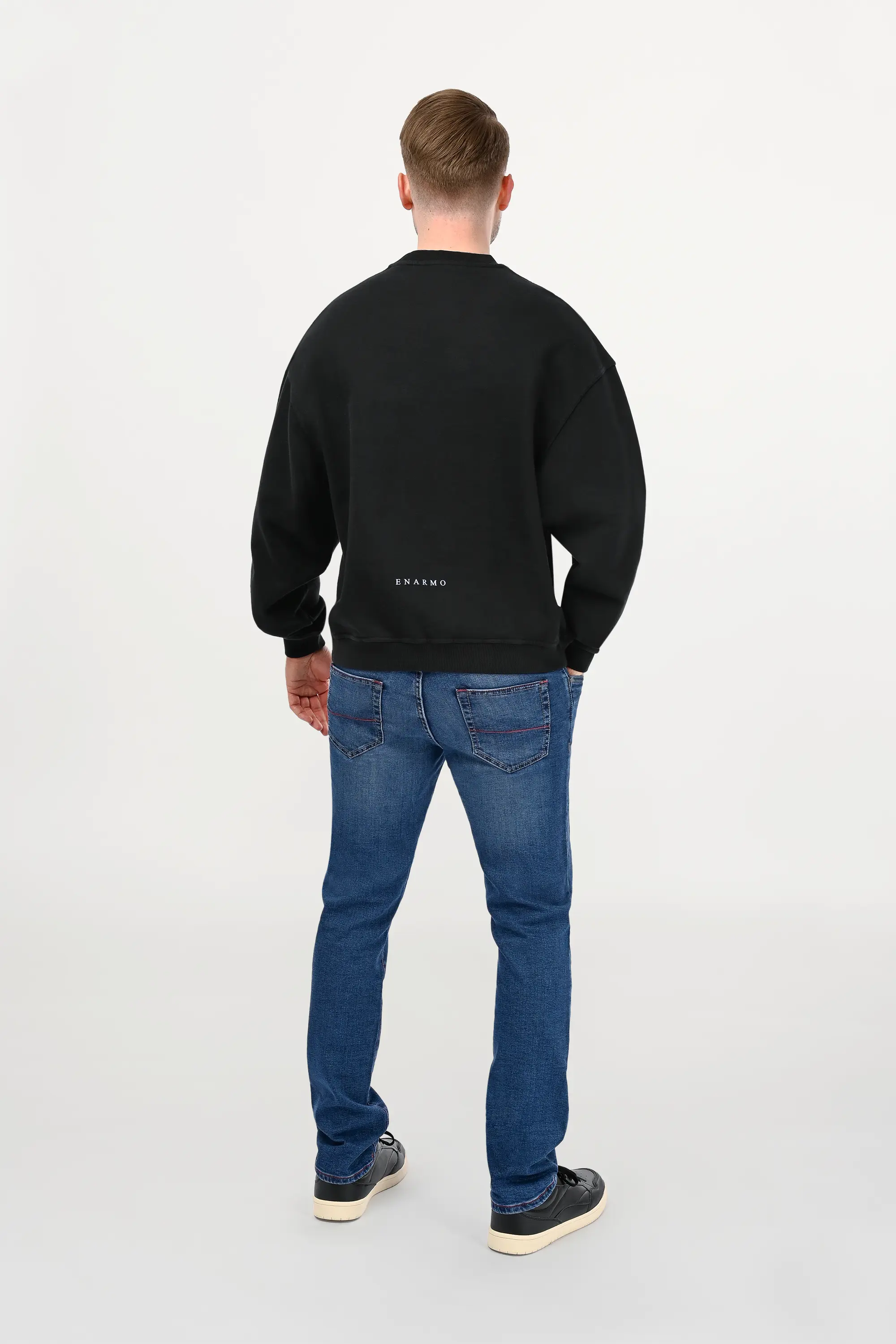 Rear view of male model in mid blue jeans, clean structure, slim fit.
