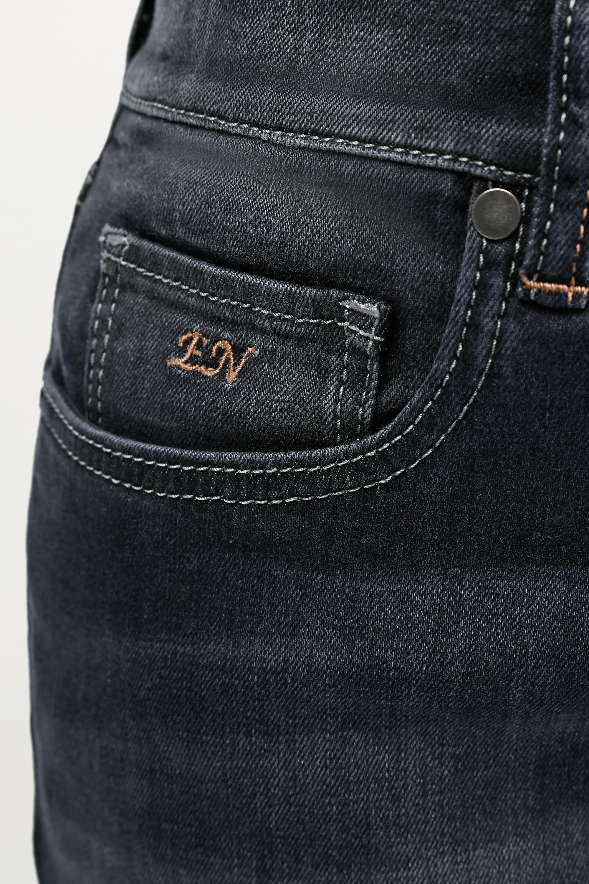 Close-up of coin pocket on mid grey women’s denim jeans with gold brown EN monogram embroidery, signature detail on premium five-pocket design.