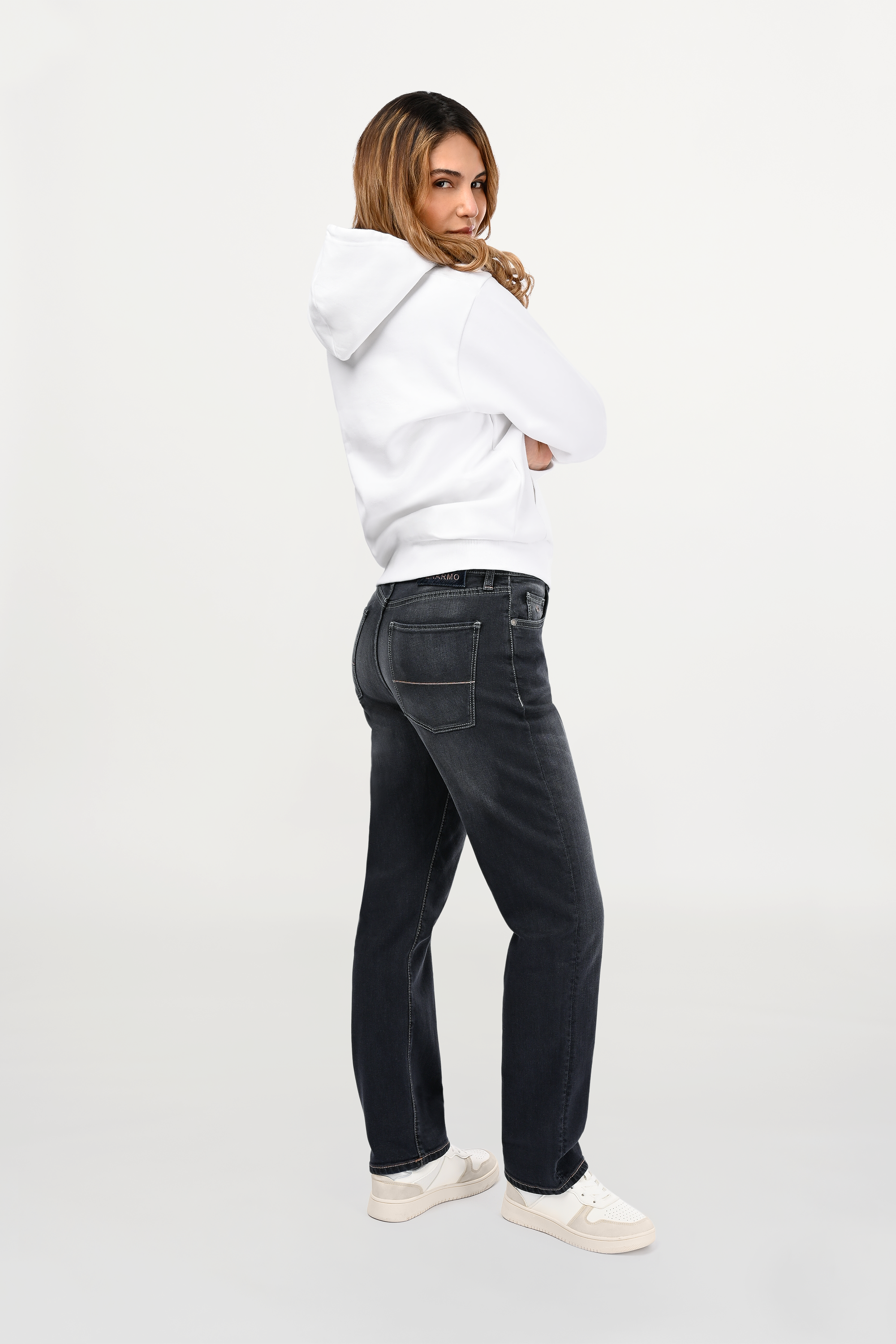 Side profile of female model wearing mid grey regular fit jeans showing smooth leg line, refined fading and contemporary everyday denim profile.
