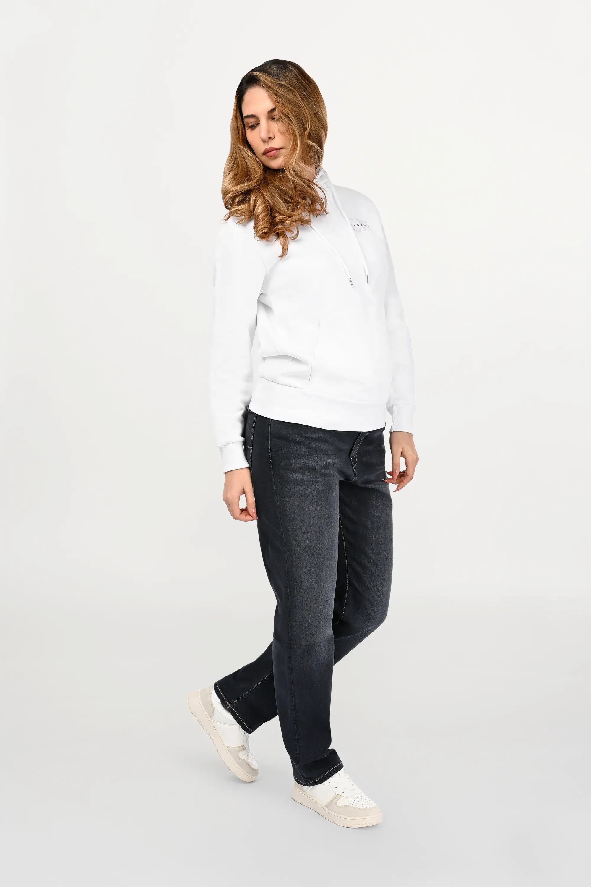 Female model wearing white cotton hoodie with beige EN monogram and black ENARMO signature on left chest, regular fit silhouette shown from angled front view.