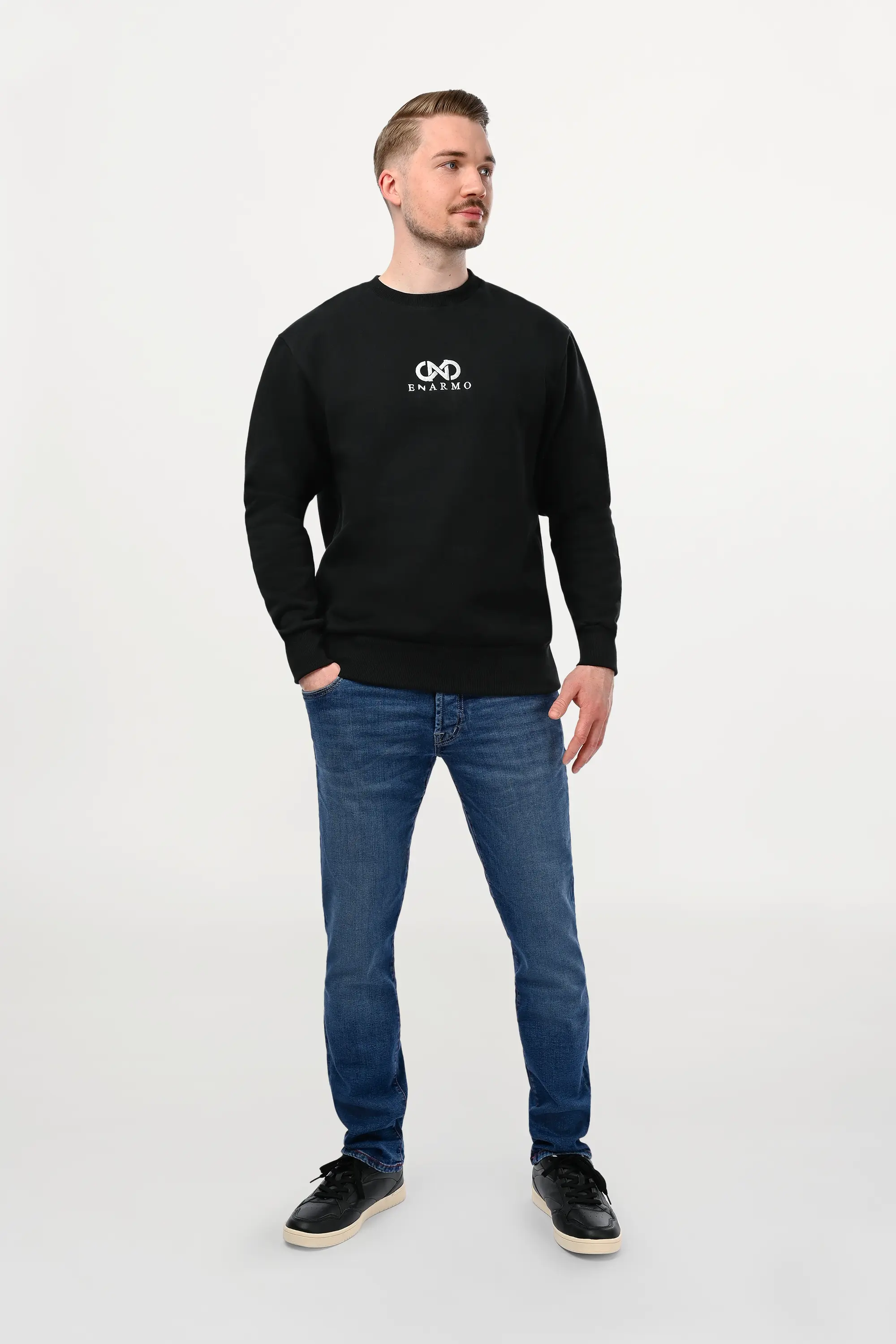 Male model wearing black cotton sweatshirt with silver ENARMO embroidery, regular cut, side gaze, refined minimalist styling.