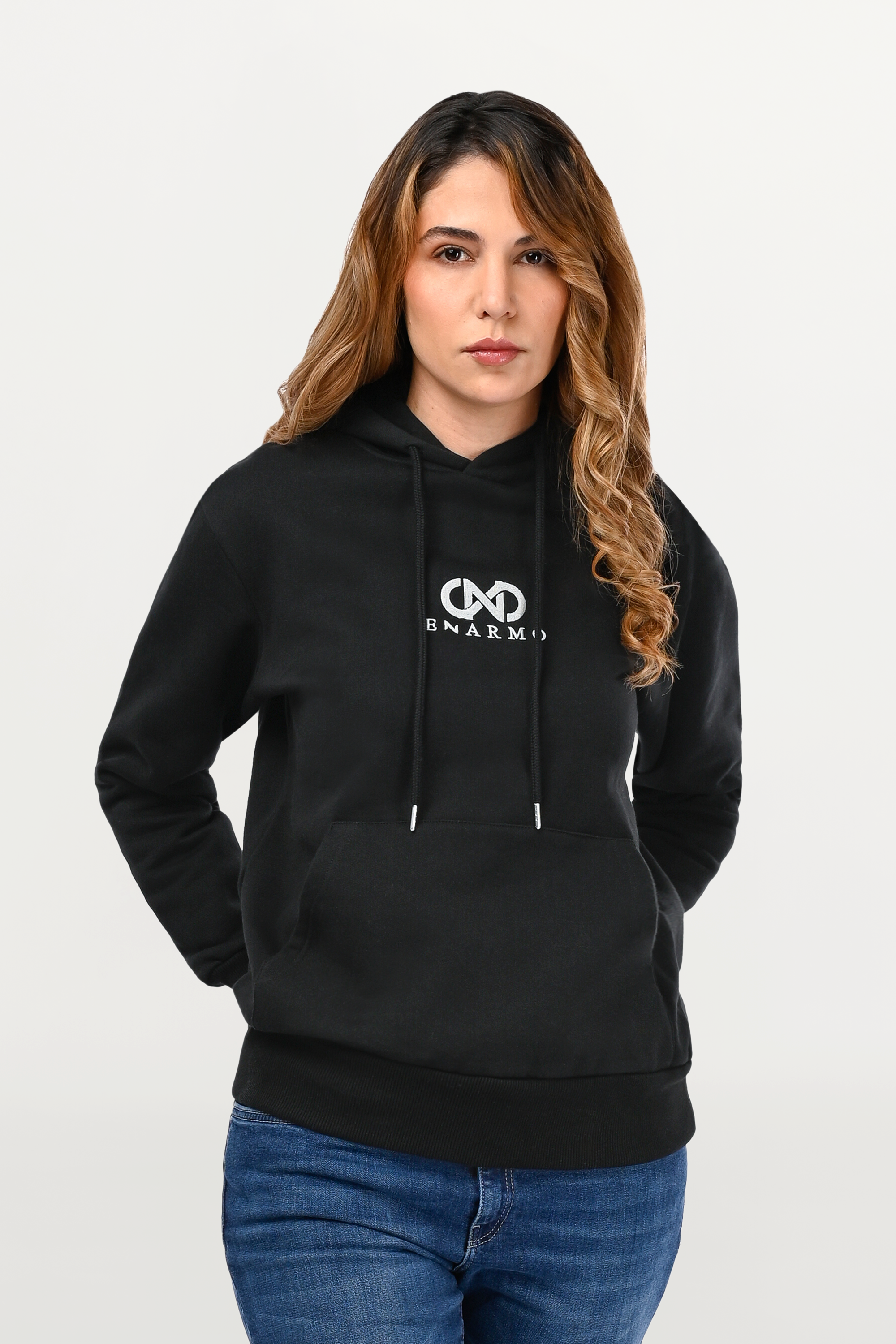 Close-up of silver embroidered ENARMO logo on black hoodie, detailed metallic stitching on smooth cotton surface.