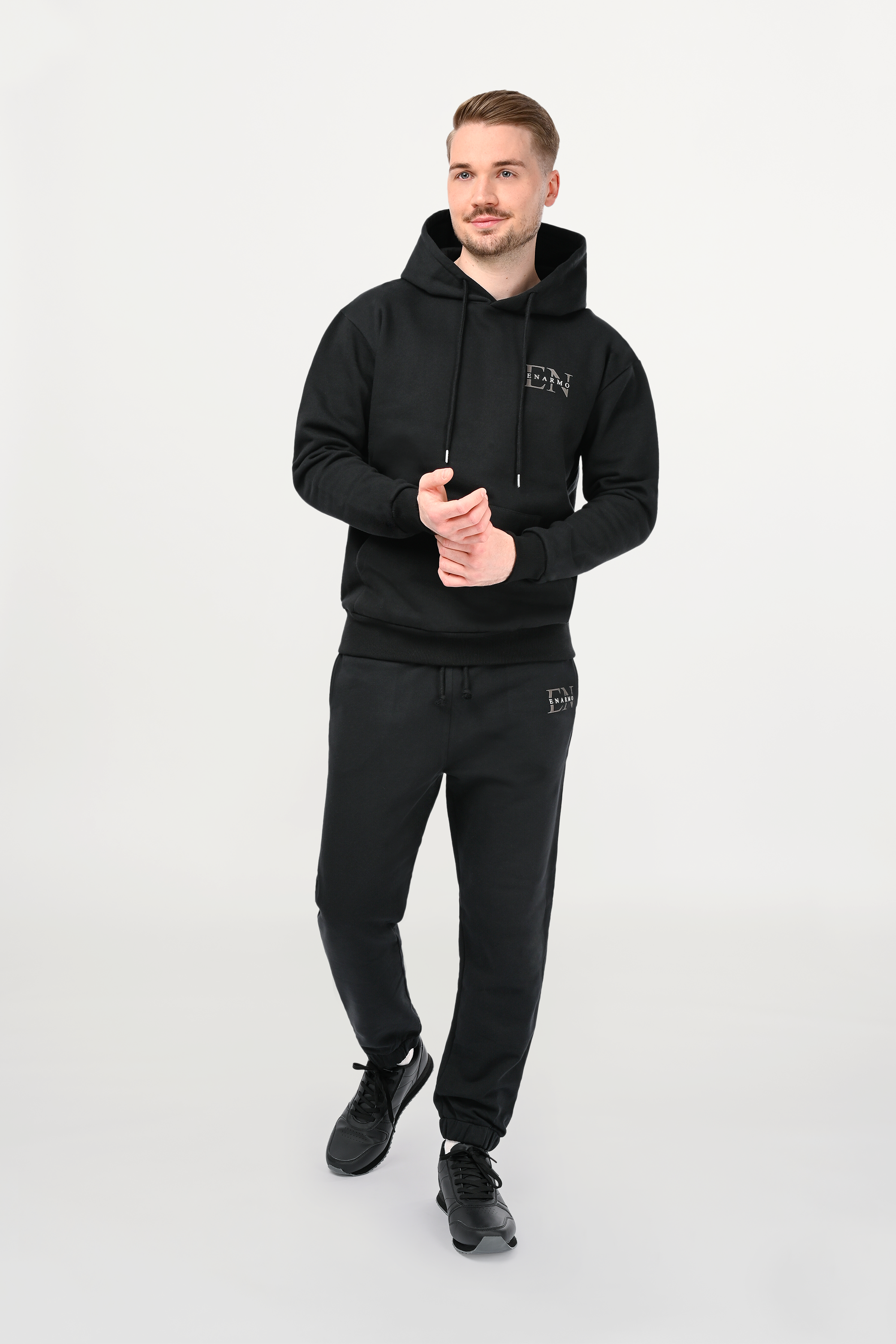 Male model wearing black cotton hoodie in regular fit with anthracite EN Monogram on left chest, structured silhouette and tailored drape.