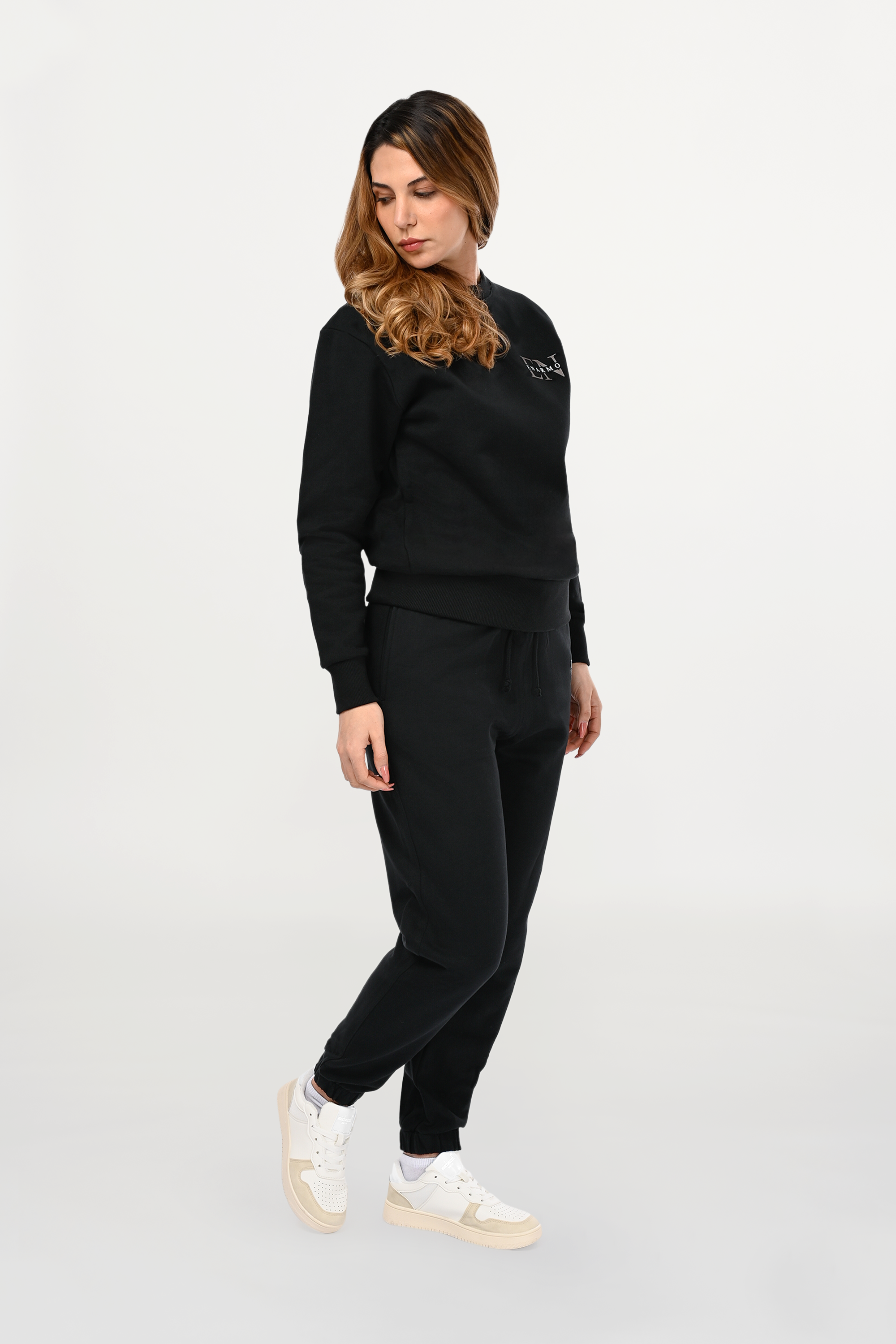 Female model wearing black cotton crewneck sweatshirt with EN monogram print on left chest in anthracite and white, regular fit and refined styling.
