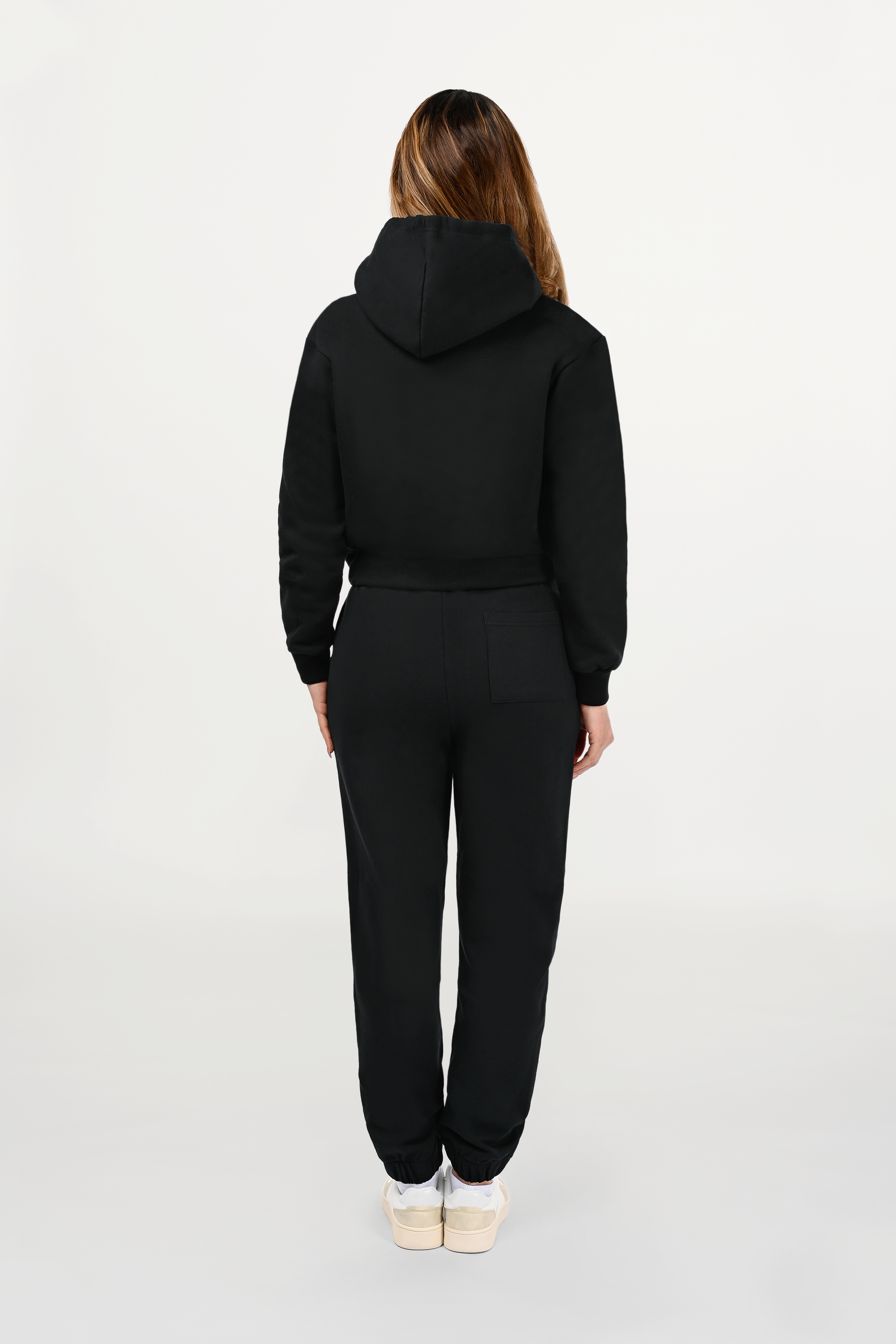 Back perspective of female model wearing black cotton hoodie, smooth rear construction and precise fit for elevated everyday wear.
