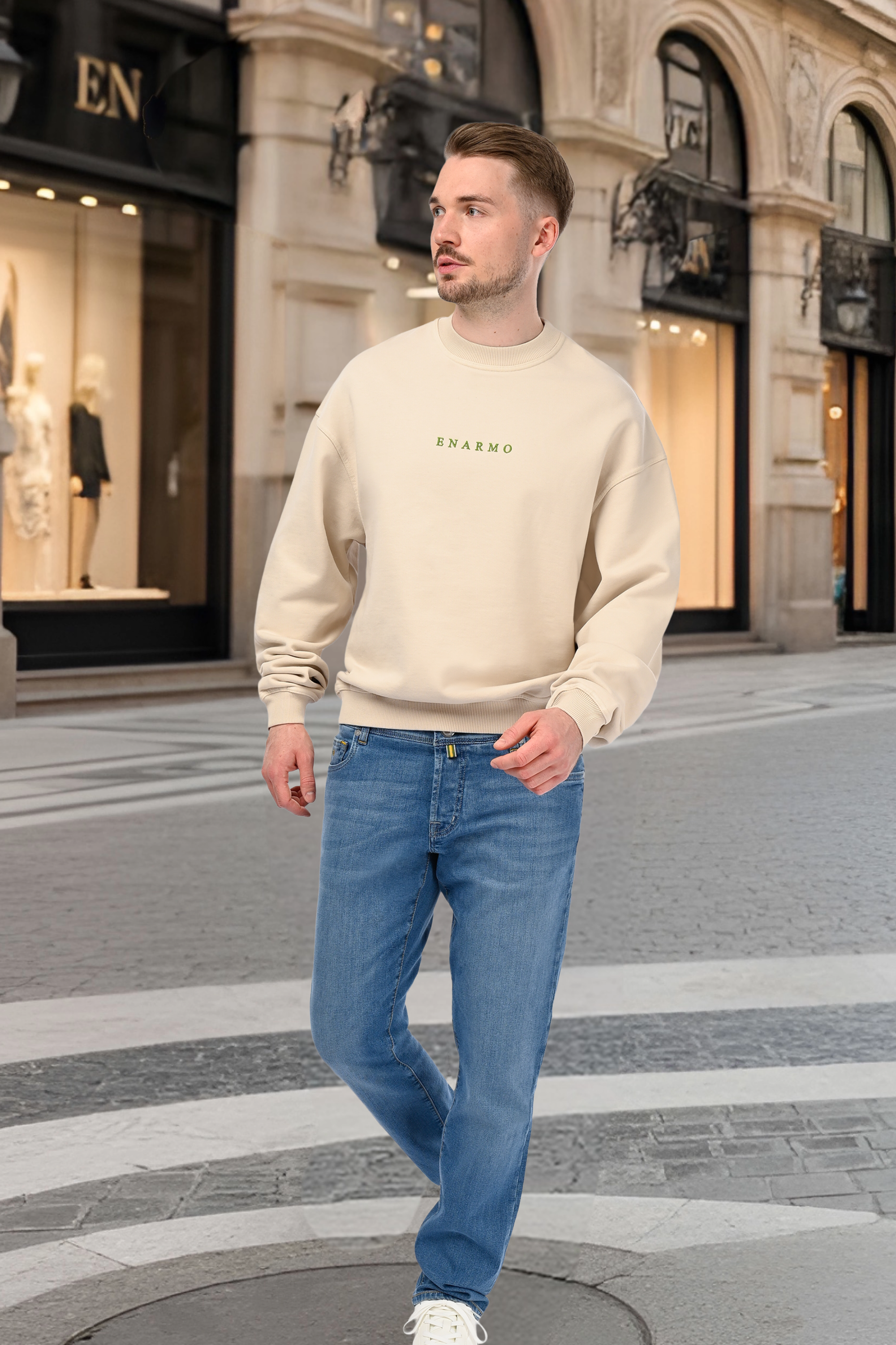 Man wearing luxury mid-blue jeans and a beige oversized sweatshirt on an Italian street