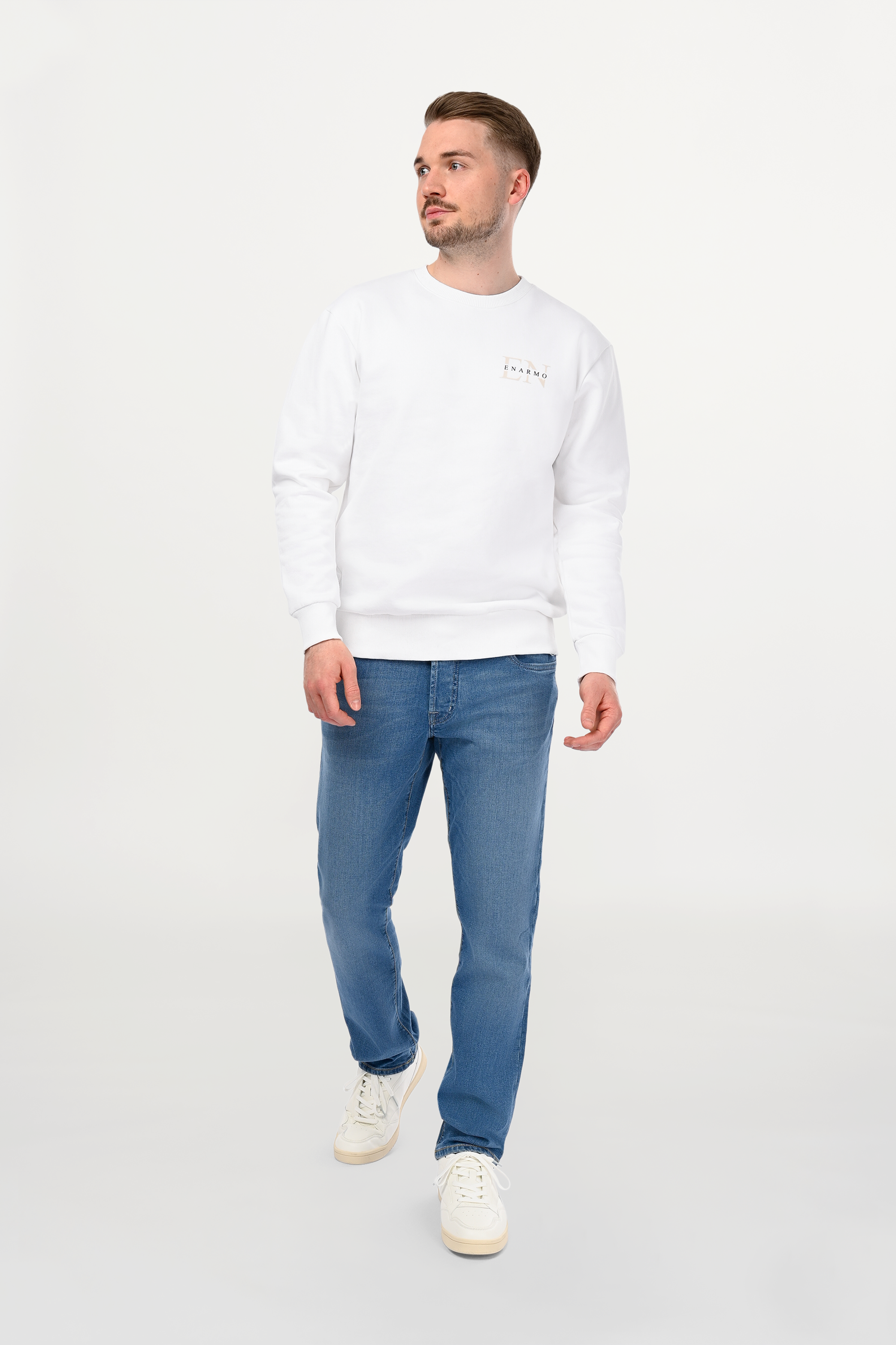 Male model wearing white cotton crewneck with beige EN monogram and black wordmark on left chest, regular fit and clean minimalist styling.