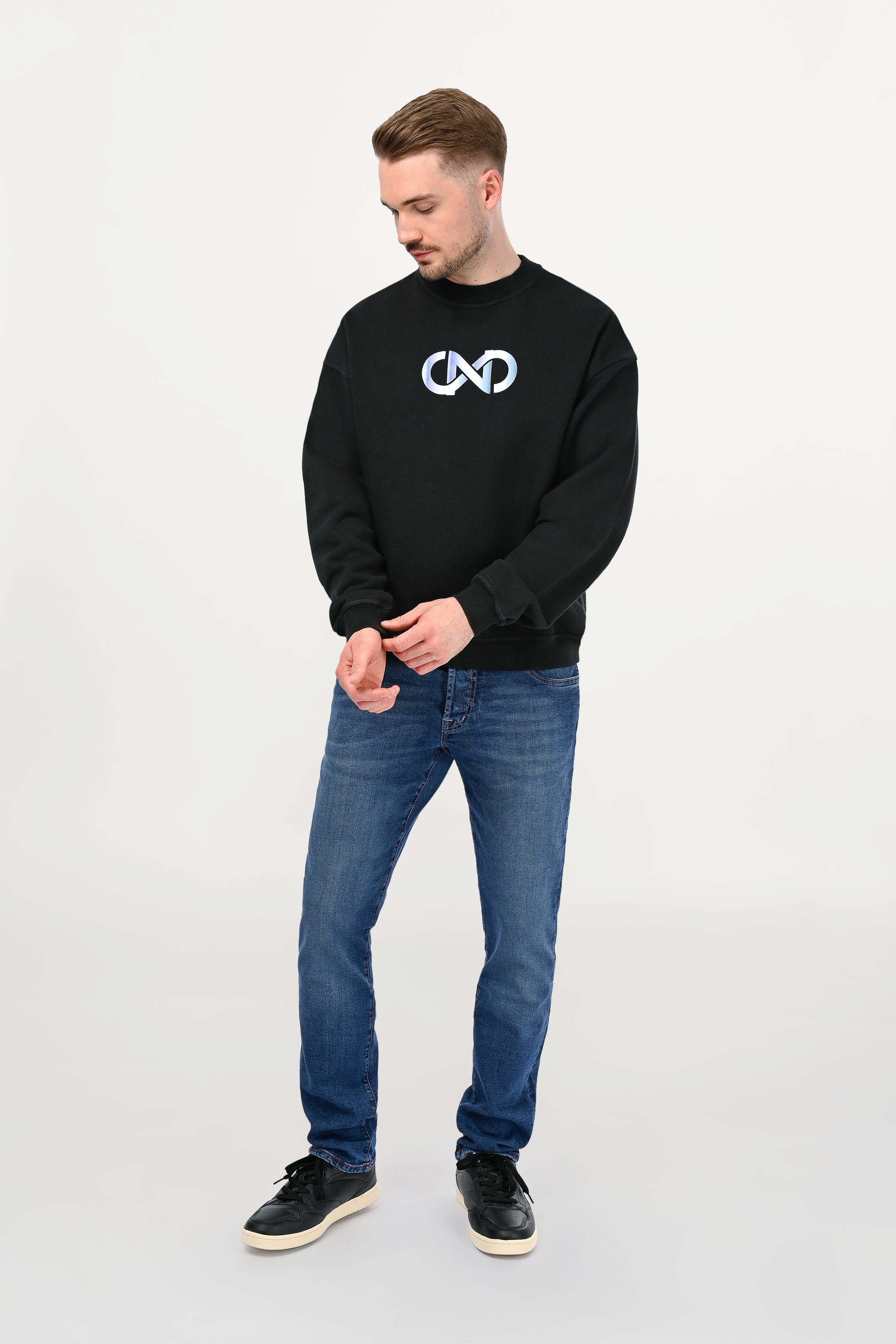 Male model wearing black oversized cotton sweatshirt with sky gradient chest print, relaxed unisex silhouette and jet black finish.