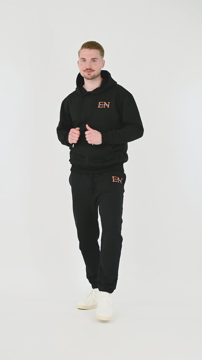 Male model wearing black cotton hoodie with orange and white EN monogram, turning, posing and moving from front, side and back to highlight fit and design from multiple angles.
