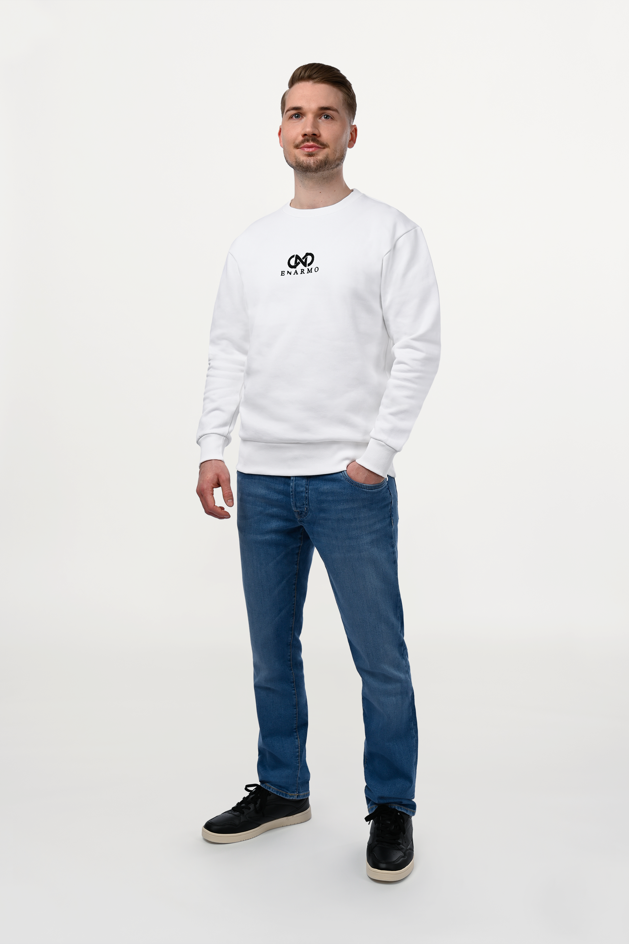 Male model wearing white cotton sweatshirt with black embroidered ENARMO logo, regular fit, minimal luxury styling.